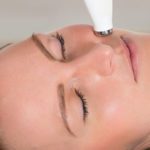 Young Woman Receiving Microdermabrasion Therapy In Beauty Clinic
