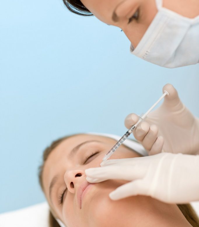 A woman getting facial injections by doctor
