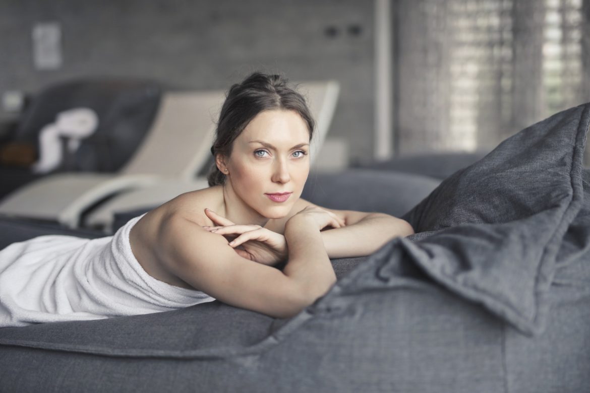 A woman laying on a couch with a towel on